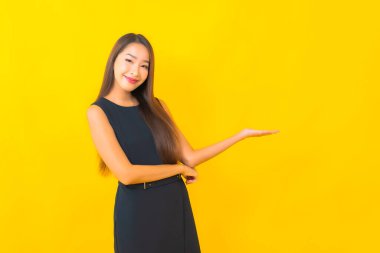 Güzel Asyalı iş kadını portresi. Sarı arka planda hareketli bir gülümseme.