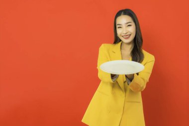 Portre güzel genç Asyalı kadın. Kırmızı arka planda boş tabağı var.