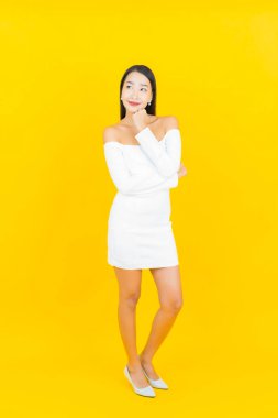 Portre güzel genç iş kadını gülümseyen ve eylem sarı arka planlı Asyalı kadın