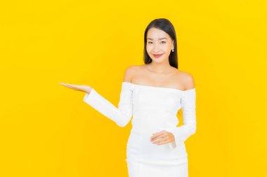 Portre güzel genç iş kadını gülümseyen ve eylem sarı arka planlı Asyalı kadın