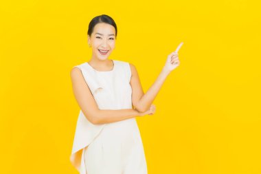 Asyalı güzel bir kadının portresi. Sarı arka planda hareketli gülümsüyor.