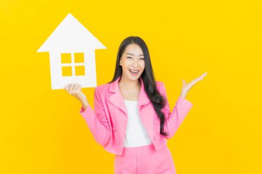 Sarı arka planda ev ya da kağıt tabelalı güzel Asyalı kadın portresi