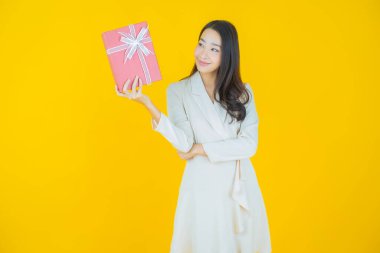 Güzel bir Asyalı kadının portresi. Arka planda kırmızı hediye kutusuyla gülümsüyor.