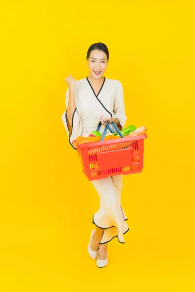노란색 배경으로 슈퍼마켓에서 바구니를 가지고 아름다운 사업가의 — 스톡 사진