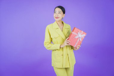 Güzel bir Asyalı kadının portresi. Arka planda kırmızı hediye kutusuyla gülümsüyor.