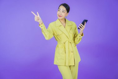 Renkli arka planda akıllı cep telefonuyla güzel Asyalı kadın gülümsemesi