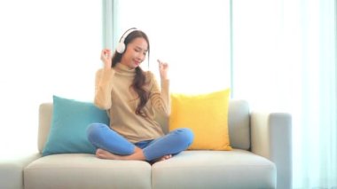 Evde kulaklıkla müzik dinleyen Asyalı güzel bir kadının görüntüleri.