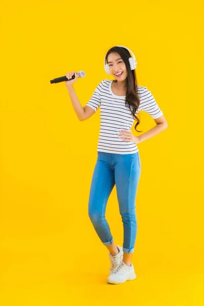 Portré Gyönyörű Fiatal Ázsiai Énekel Mikrofonnal Fejhallgatóval Sárga Elszigetelt Háttér — Stock Fotó