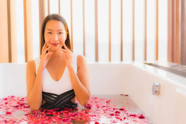 美丽的年轻亚洲女人在浴缸里快乐地微笑着 带着玫瑰花为温泉的概念 — 图库照片