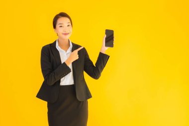 Portre güzel genç Asyalı kadın akıllı cep telefonu ve kahve fincanı ile izole edilmiş sarı arka planda