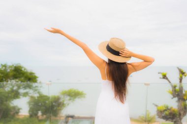 Portriat güzel genç Asyalı kadın deniz manzaralı balkonda mutlu bir gülümseme