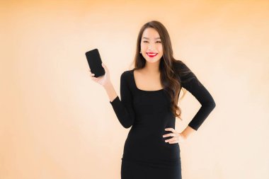 Güzel Asyalı genç bir kadının portresi mutlu bir şekilde gülümsüyor renkli arka planda akıllı cep telefonu kullan