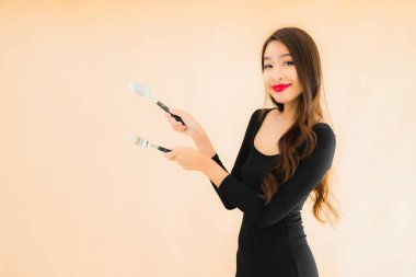 Kaşığı ve çatalı olan güzel Asyalı bir kadının portresi izole edilmiş renkli arka planda yemeye hazır.