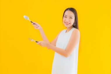 Sarı izole arka planda çatal kaşıklı güzel bir Asyalı kadın portresi.