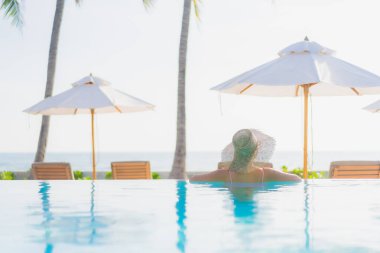 Güzel bir Asyalı kadın portresi. Tatil gezisinde deniz manzaralı açık havuz etrafında rahatça yüzebiliyor.