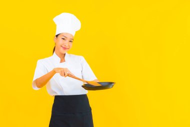 Sarı izole arka planda siyah şapkalı güzel Asyalı şef kadın portresi.