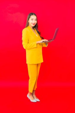 Portre güzel genç iş kadını Asyalı kadın kırmızı arka planda bilgisayar bilgisayarı kullanıyor