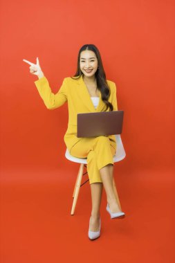 Portre güzel genç iş kadını Asyalı kadın kırmızı arka planda bilgisayar bilgisayarı kullanıyor