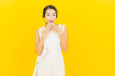 Sarı arka planda çağrı merkezi müşteri hizmetleri merkezi olan güzel Asyalı kadın portresi