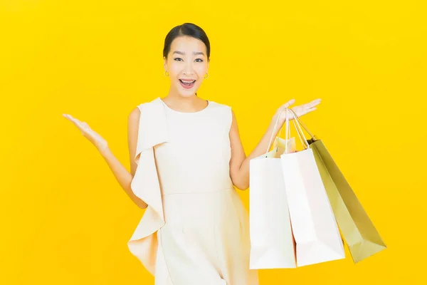 Sarı Arka Planda Alışveriş Çantasıyla Gülümseyen Güzel Asyalı Kadın Portresi — Stok fotoğraf