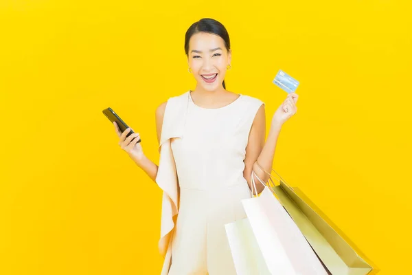 Sarı Arka Planda Alışveriş Çantasıyla Gülümseyen Güzel Asyalı Kadın Portresi — Stok fotoğraf