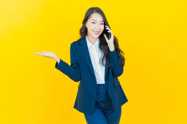 亚洲年轻貌美的女人带着聪明的手机 带着彩色背景的微笑 — 图库照片