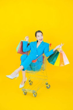 Renkli arka planda süpermarketten alınmış market sepetiyle gülümseyen güzel Asyalı kadın portresi.