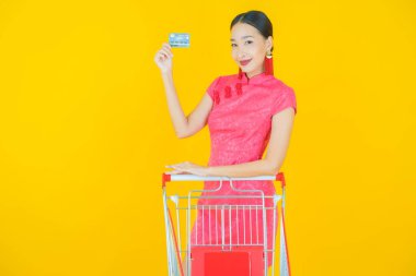 Renkli arka planda süpermarketten alınmış market sepetiyle gülümseyen güzel Asyalı kadın portresi.