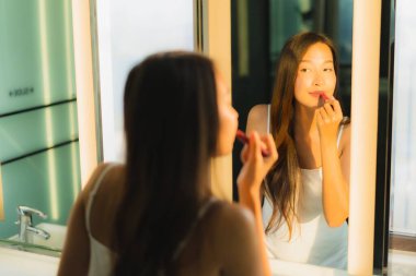 Güzel bir Asyalı kadın portresi makyaj malzemesi makyaj malzemesi ve yüz makyajı ile banyo içinde yüz maskesi.