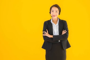 Portre güzel genç Asyalı kadın kulaklık ya da çağrı merkezi için kulaklık ya da tele pazarlama sarı izole arka planda.