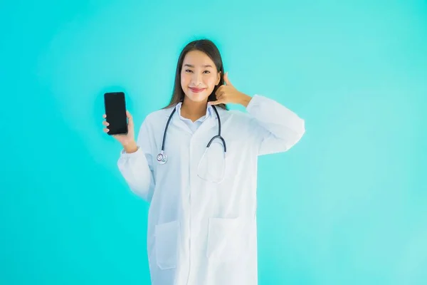 在蓝色隔离背景下 亚洲年轻貌美的女医生用手机在诊所或医院看病 — 图库照片