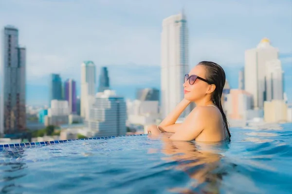 亚洲年轻貌美的女子在户外游泳池和城市景观中悠闲自在地笑容满面 — 图库照片