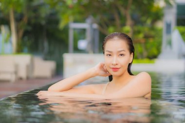 Güzel bir Asyalı kadın portresi. Rahatlayın. Yüzme havuzu etrafında gülümseyin.
