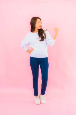 Portrait beautiful young asian woman smile with action on pink isolated background