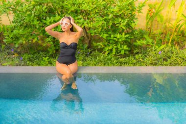 Güzel bir Asyalı kadının portresi tatil için yüzme havuzunda rahatlıyor.