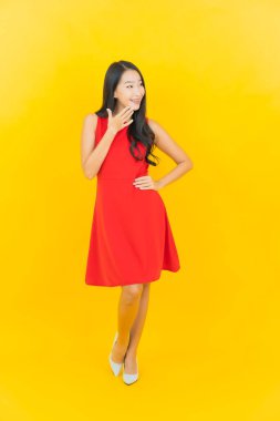 Güzel bir portre genç Asyalı kadın kırmızı elbiseler giyip sarı arka planda hareketli bir gülümseme takın.