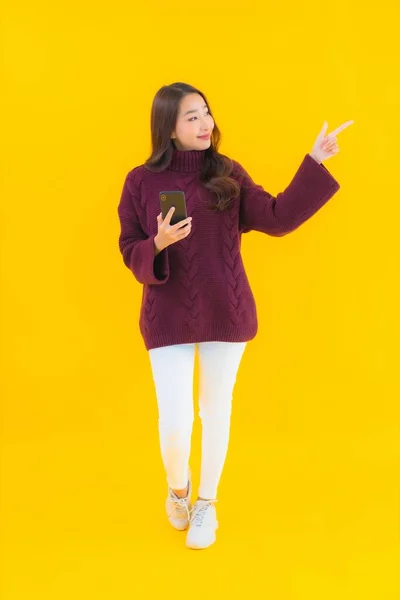 形象漂亮的年轻亚洲女人在黄色隔离背景下使用智能手机 — 图库照片
