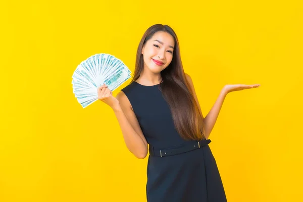 肖像画美しい若いアジアのビジネス女性とともに多くの現金とお金で黄色の背景 — ストック写真