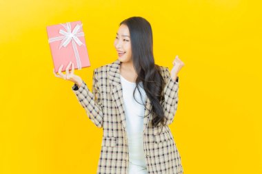 Güzel bir Asyalı kadının portresi. Arka planda kırmızı hediye kutusuyla gülümsüyor.