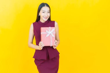 Güzel bir Asyalı kadının portresi. Arka planda kırmızı hediye kutusuyla gülümsüyor.