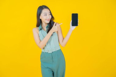 Renkli arka planda akıllı cep telefonuyla güzel Asyalı kadın gülümsemesi