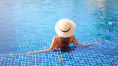 Otelde yüzme havuzunda dinlenen Asyalı güzel bir kadının görüntüsü.