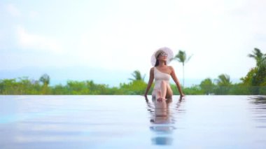 Otelde yüzme havuzunda dinlenen Asyalı güzel bir kadının görüntüsü.