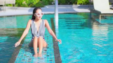 Otelde yüzme havuzunda dinlenen Asyalı güzel bir kadının görüntüsü.