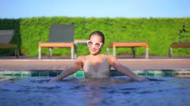 Otelde yüzme havuzunda dinlenen Asyalı güzel bir kadının görüntüsü.