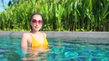 Otelde yüzme havuzunda dinlenen Asyalı güzel bir kadının görüntüsü.