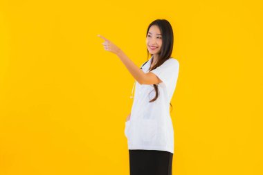 Güzel bir portre genç Asyalı kadın gülümsüyor. Hastane ve klinikte çalışmanın mutluluğu sarı izole edilmiş arka planda.