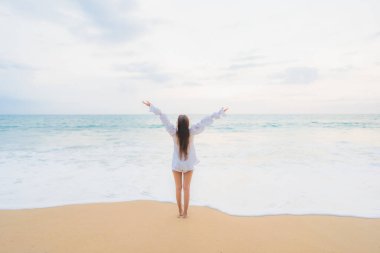 Güzel bir Asyalı kadın portresi deniz kenarında tatil yaparken rahatlar.