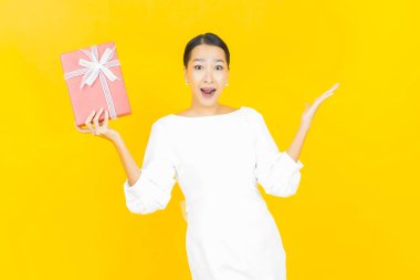 Güzel bir Asyalı kadının portresi. Arka planda kırmızı hediye kutusuyla gülümsüyor.