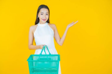 Renkli arka planda süpermarketten alınmış market sepetiyle gülümseyen güzel Asyalı kadın portresi.